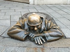 Čumil, estatua d eun trabajador asomando por la alcantarilla